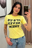 Camiseta Lerrux Babylook Film Never amarela com estampa preta 'IT'S US NEVER THEM' vestida na modelo, frente