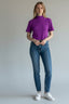 Blusa Groovy Cropped Gola Canelada roxa com manga curta, vestida na modelo com calça jeans e tênis branco