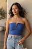 Blusa cropped Cacay azul com detalhe em aro, vestida em modelo sorridente com calça jeans e bolsa de palha