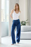 Calça jeans reta Skenn azul com estampa de pequenos pontos, vestida em modelo com body branco e sandálias