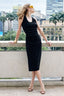 Vestido Skenn preto de tule com pontinhos, decote redondo e franzidos laterais, usado por modelo em varanda urbana