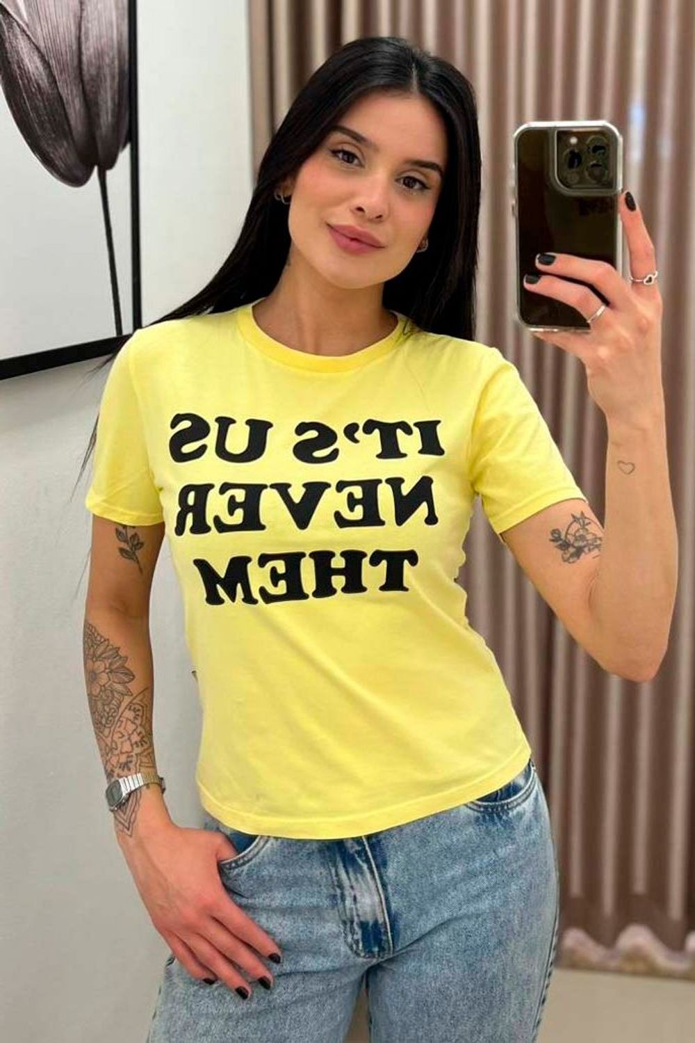 Camiseta Lerrux Babylook Film Never amarela com estampa preta 'IT'S US NEVER THEM' vestida na modelo, frente