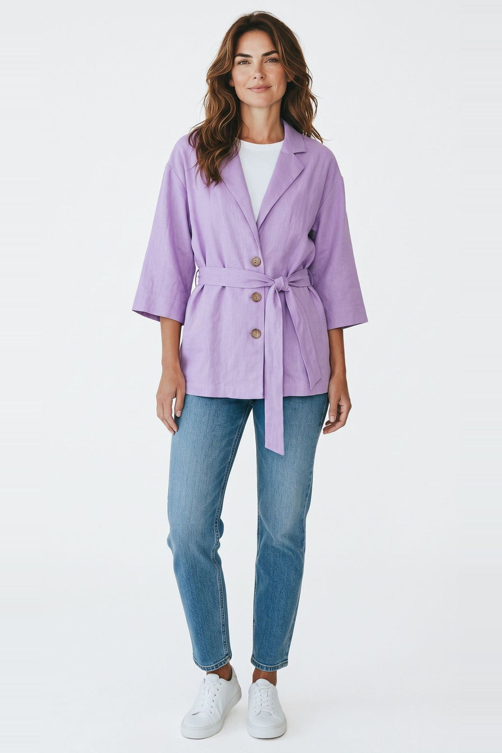 Blazer Skenn lilás com cinto amarrado na cintura, vestido em modelo com jeans e tênis brancos