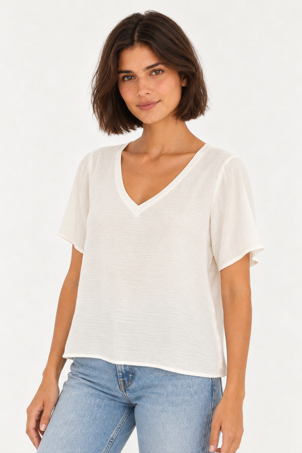 Branco | Blusa Básica Gola V Manga Curta Aishty branca com mangas levemente soltas, vestida na modelo, vista de três quartos