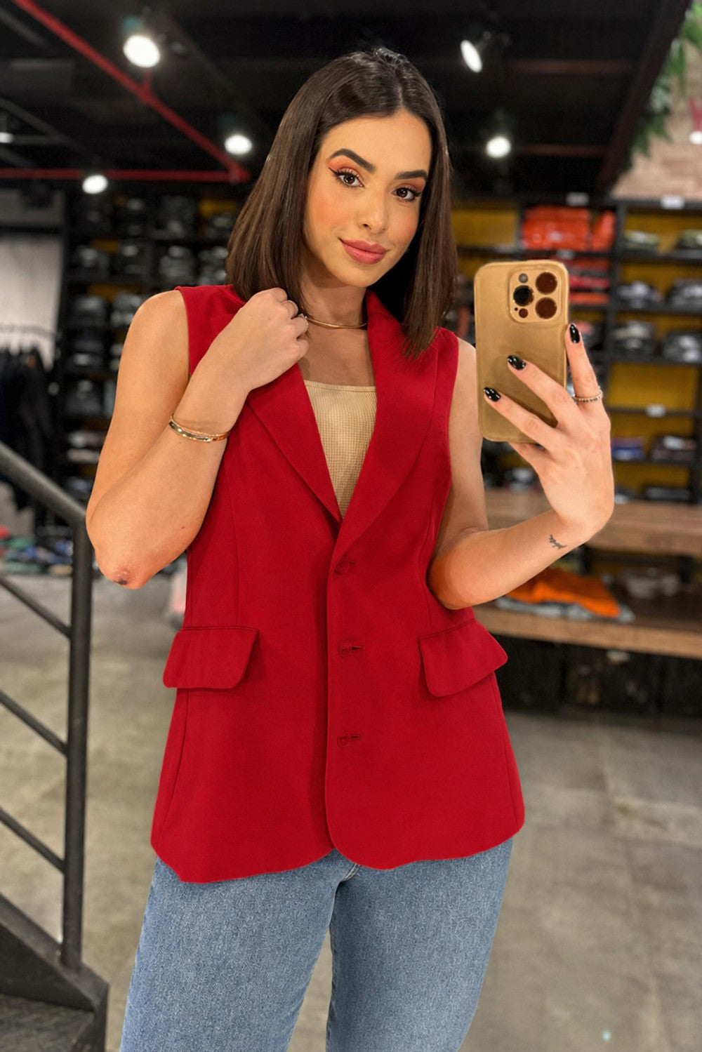Blusa colete alfaiataria Skenn vermelha, com decote em V, botões e bolsos de aba, usada por modelo com jeans Imagem principal do produto
