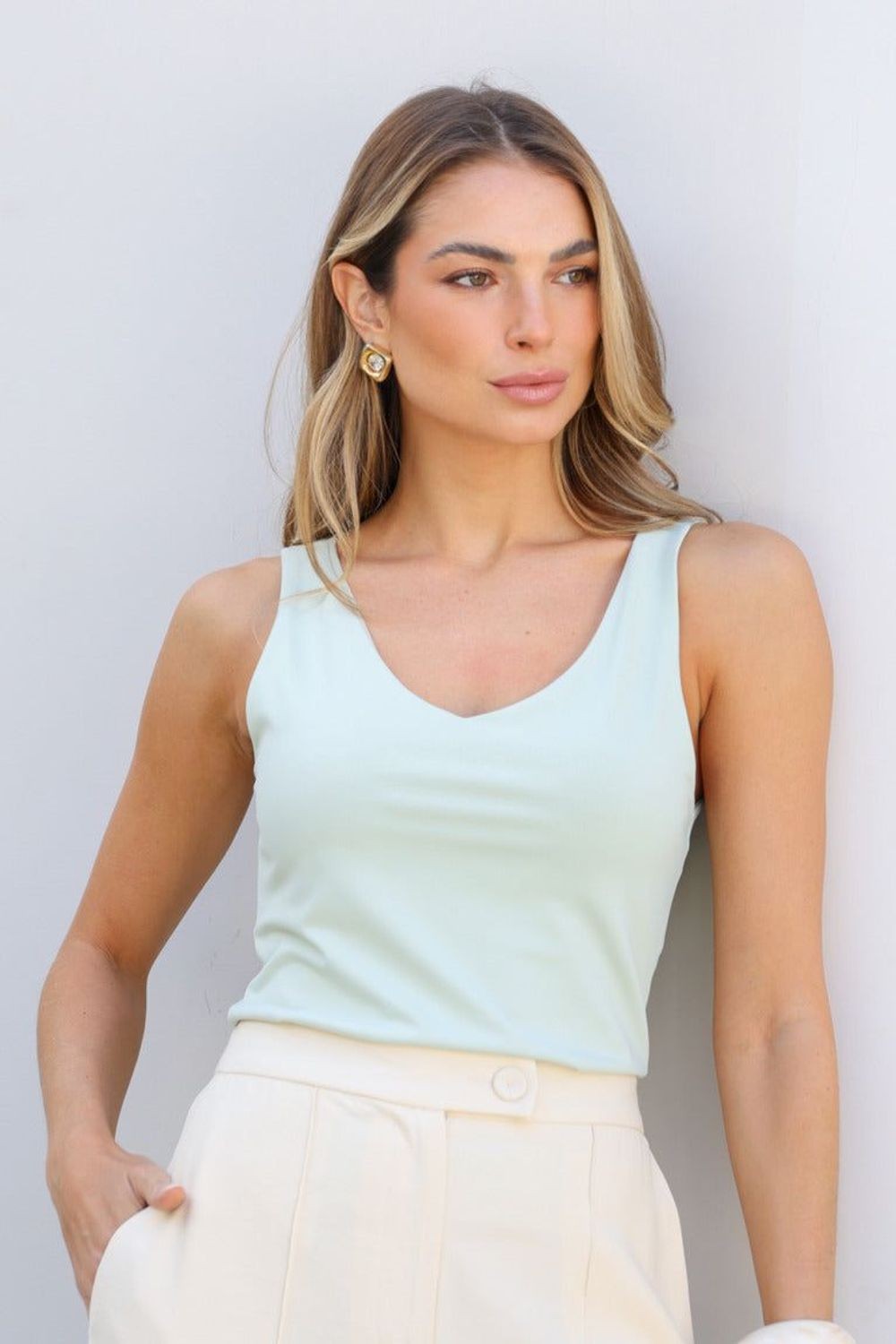 Blusa Skenn Decote Soft verde menta com decote em V, vestida em modelo com calça off-white de cintura alta Imagem principal do produto