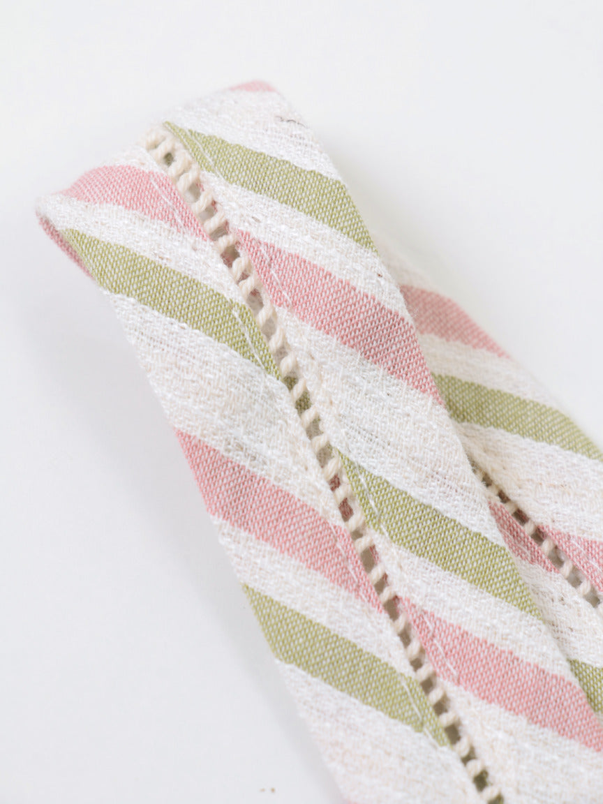 Detalhe do tecido listrado verde, rosa e off-white da alça da blusa Skenn Listrada Resort, com acabamento de costura aparente