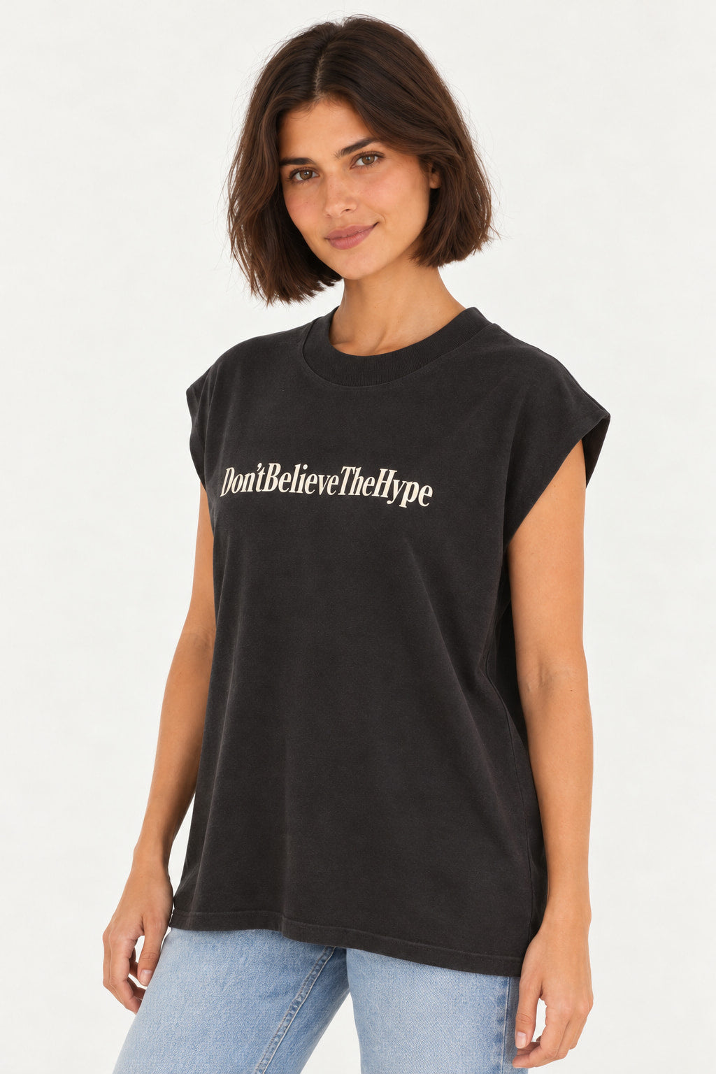 Preto | Blusa regata Lerrux preta com estampa Don't Believe The Hype em letras brancas, modelo de frente com jeans azul