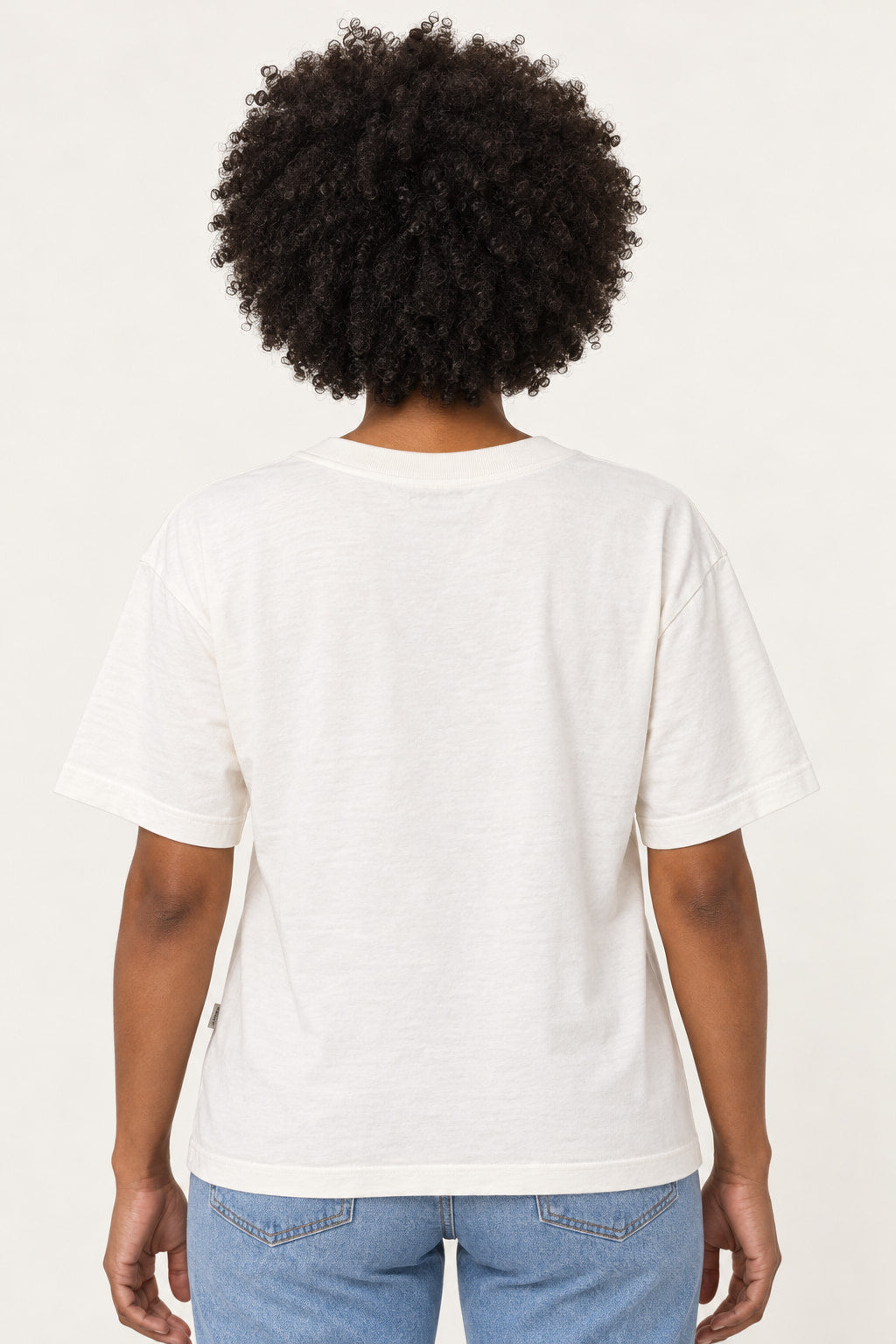Off | Blusa T-Shirt Born Lerrux off-white vista de costas na modelo, com gola redonda e malha lisa, combinada com calça jeans