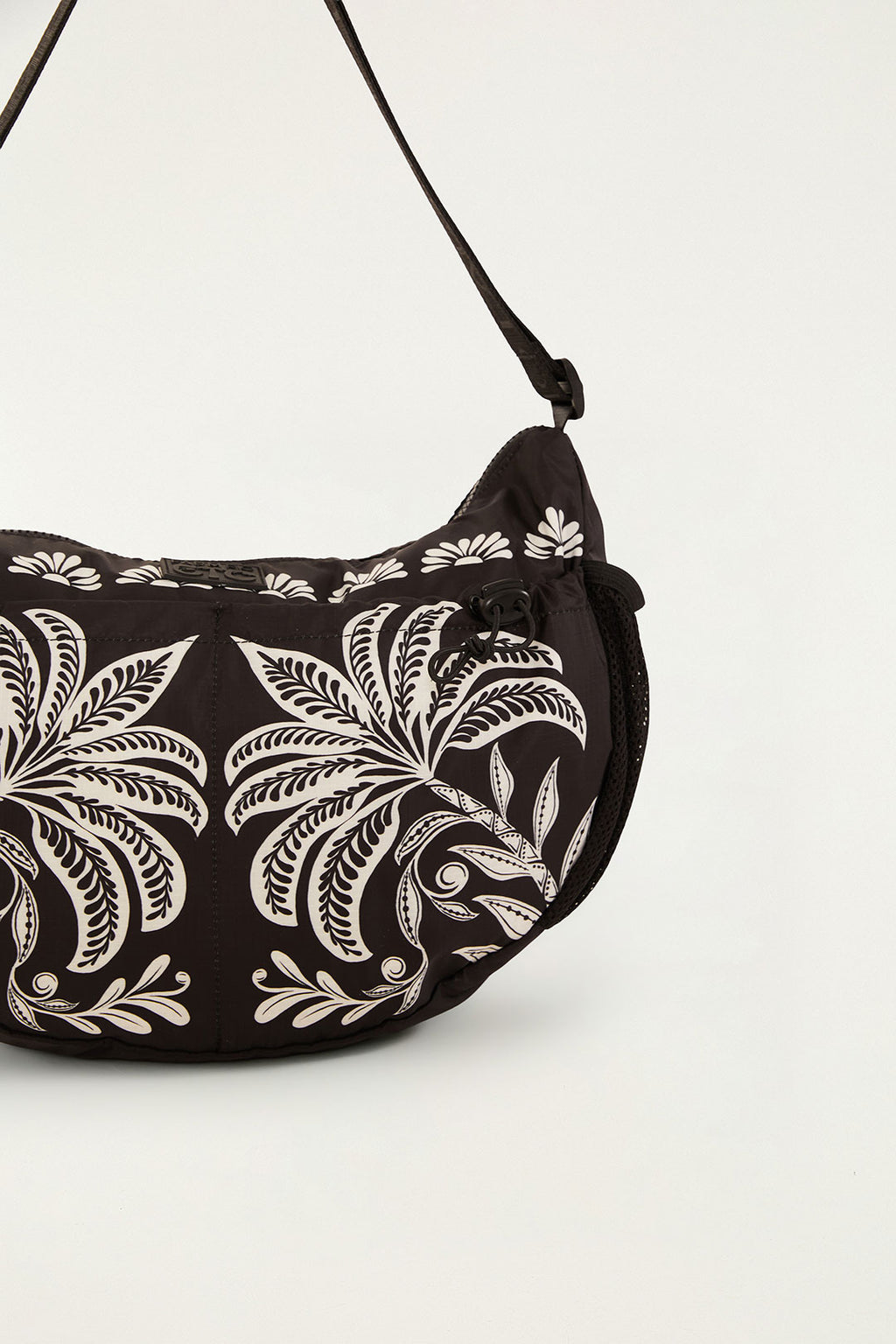 Bolsa Farm Banana G Coqueiro Sereno preta com estampa de coqueiros brancos e cordão com trava, detalhe da lateral