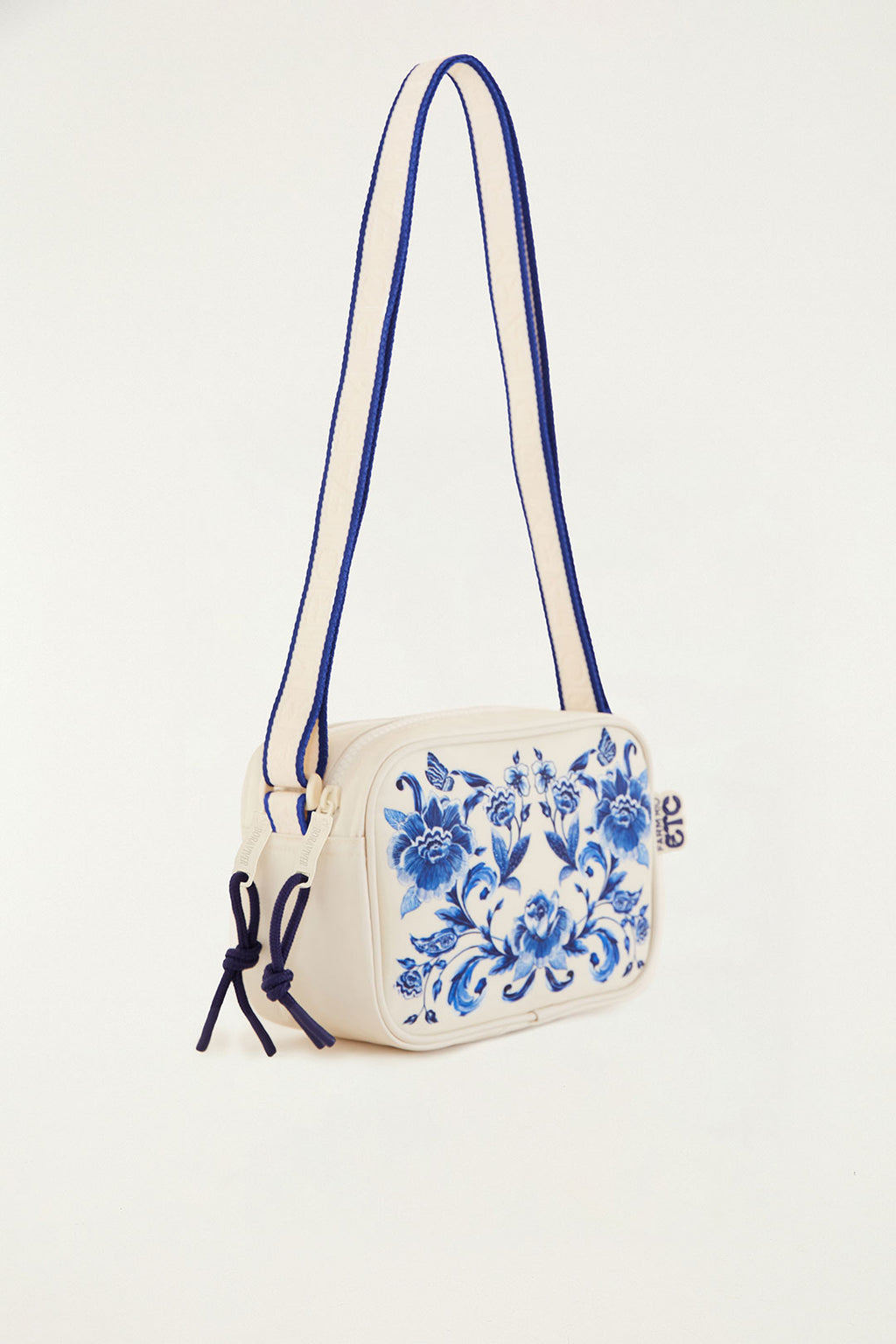 Bolsa Farm Chamego Porcelain em off-white com estampa floral azul, vista lateral com alça em listras azuis
