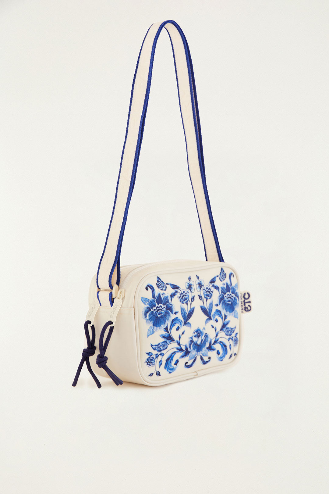 Bolsa Farm Chamego Porcelain em off-white com estampa floral azul, vista lateral com alça em listras azuis