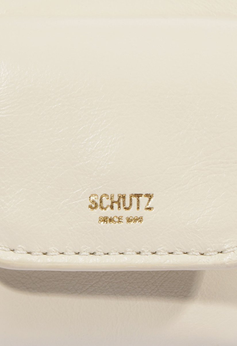 Detalhe do logo Schutz dourado gravado no couro off-white da bolsa Hobo Mini Lilo
