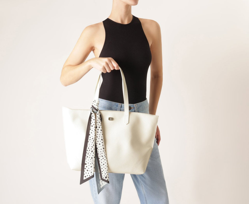 Modelo segurando a bolsa Anacapri Shopping Grande Lenço Pontilhado branca no ombro com blusa preta e calça jeans clara