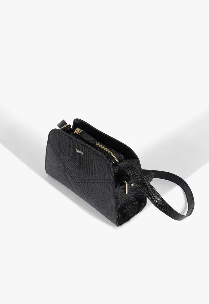 Bolsa tiracolo Schutz Hazel Pequena preta deitada, mostrando o interior com zíper dourado e alça longa