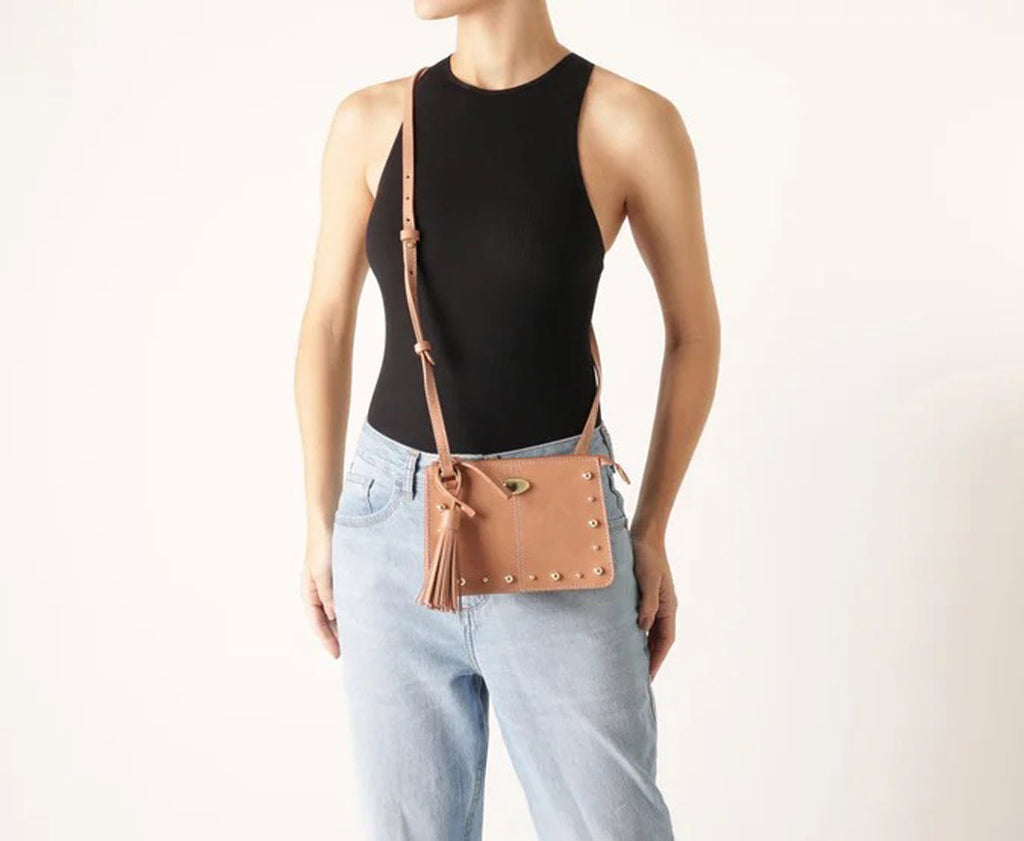 Modelo vestindo body preto e jeans claro com bolsa tiracolo Anacapri Boho bege no ombro
