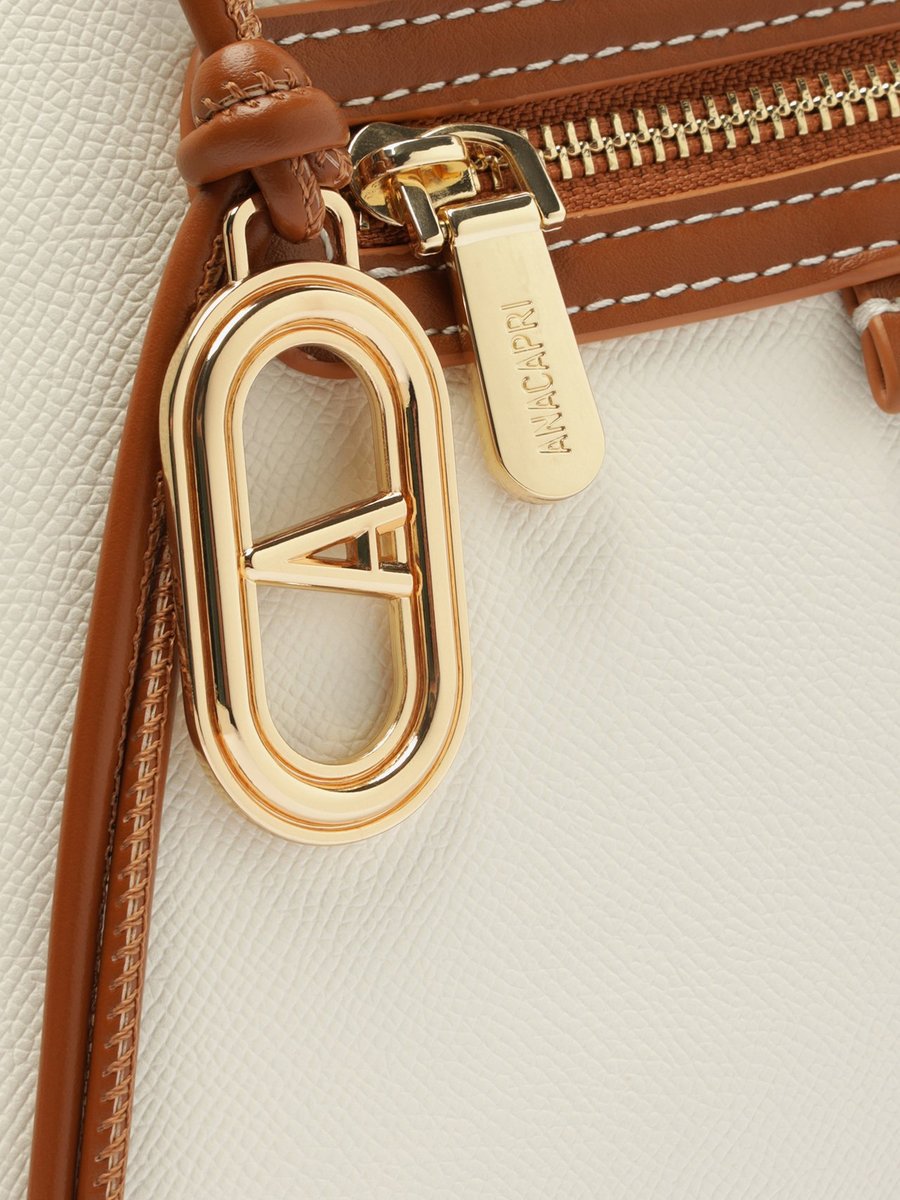 Detalhe da bolsa Anacapri Charm Cadarço branca com o logo Anacapri gravado no zíper e o pingente dourado