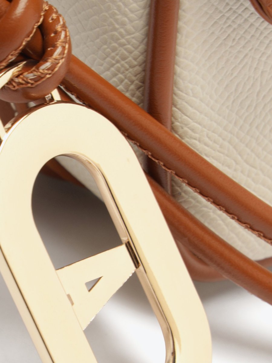 Bolsa Anacapri Maleta Charm branca em close no charm dourado e na alça de couro caramelo trançada