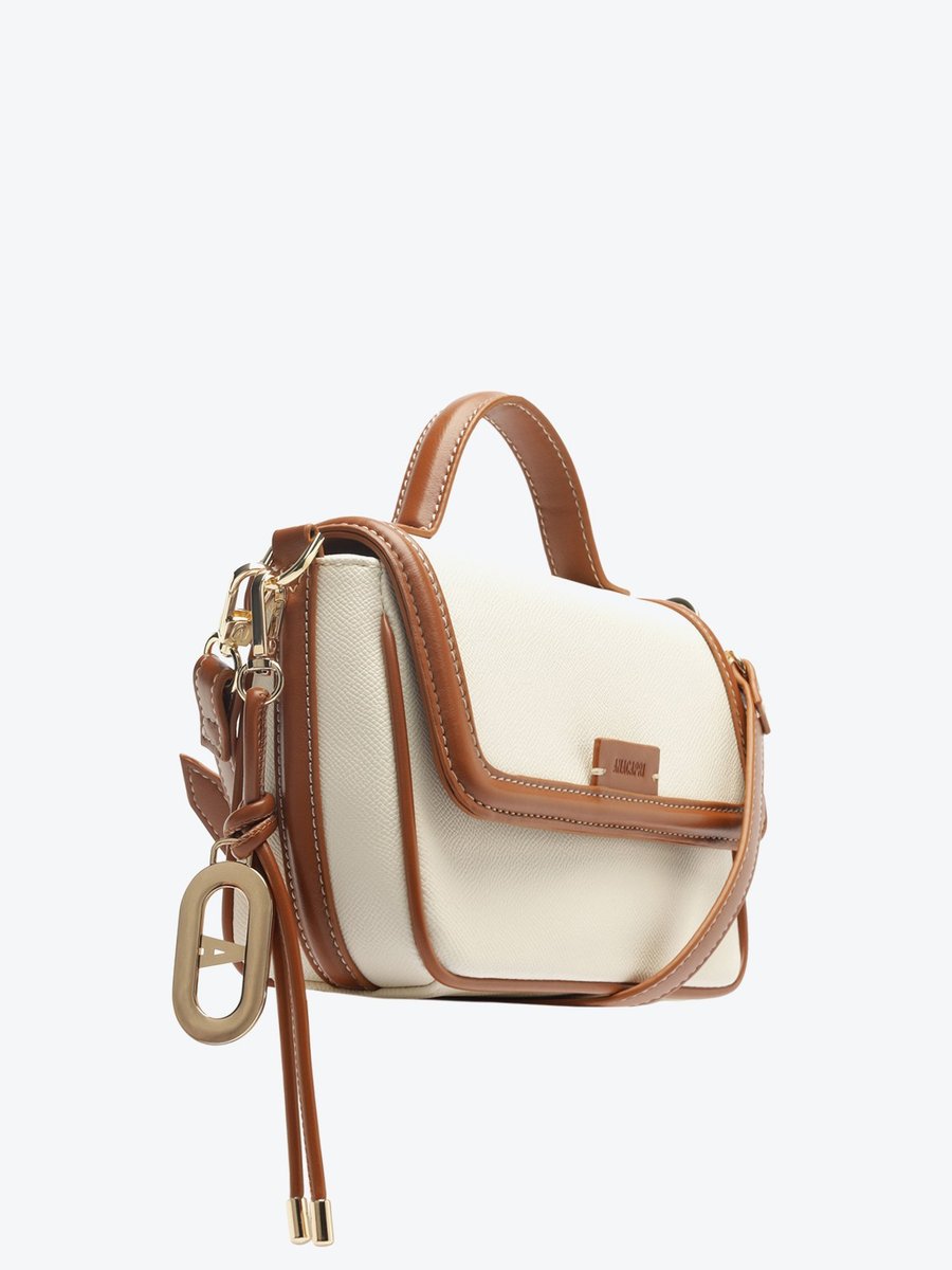 Bolsa tiracolo Anacapri Maleta Charm branca com acabamento caramelo, vista lateral mostrando a aba e o charm dourado