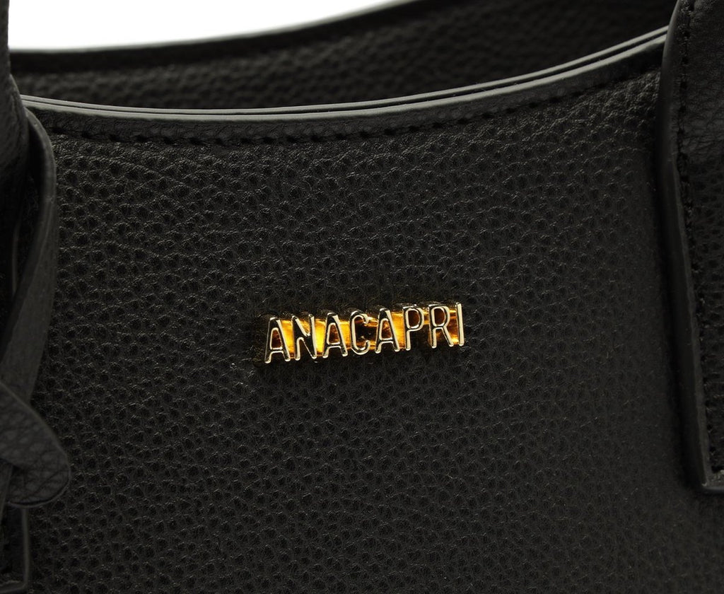 Detalhe da logomarca Anacapri dourada na bolsa Tote preta de textura granulada