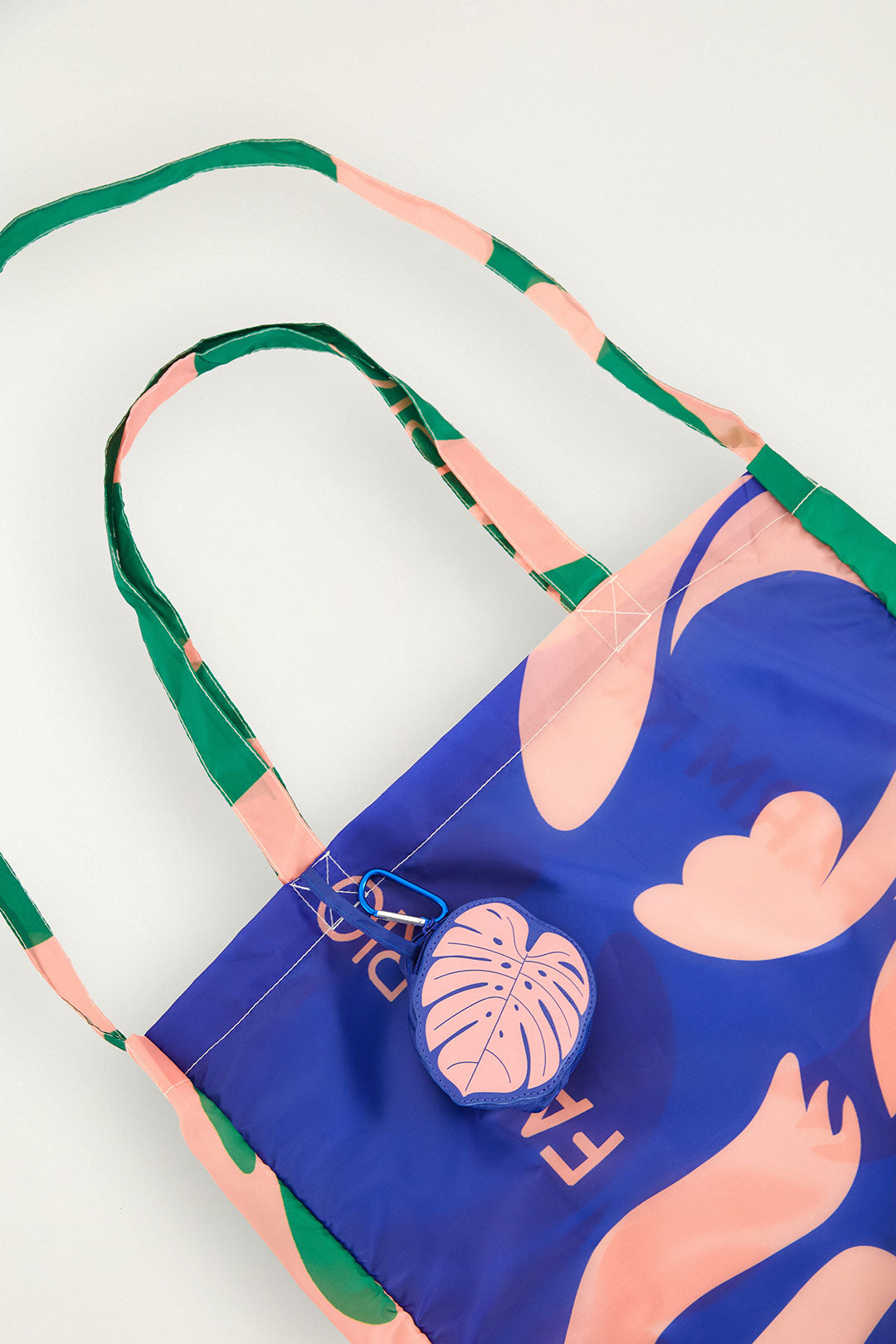 Bolsa Farm Me Leva Lisos Farm Etc estampada em azul e rosa com alças verdes, vista de cima com chaveiro de folha preso