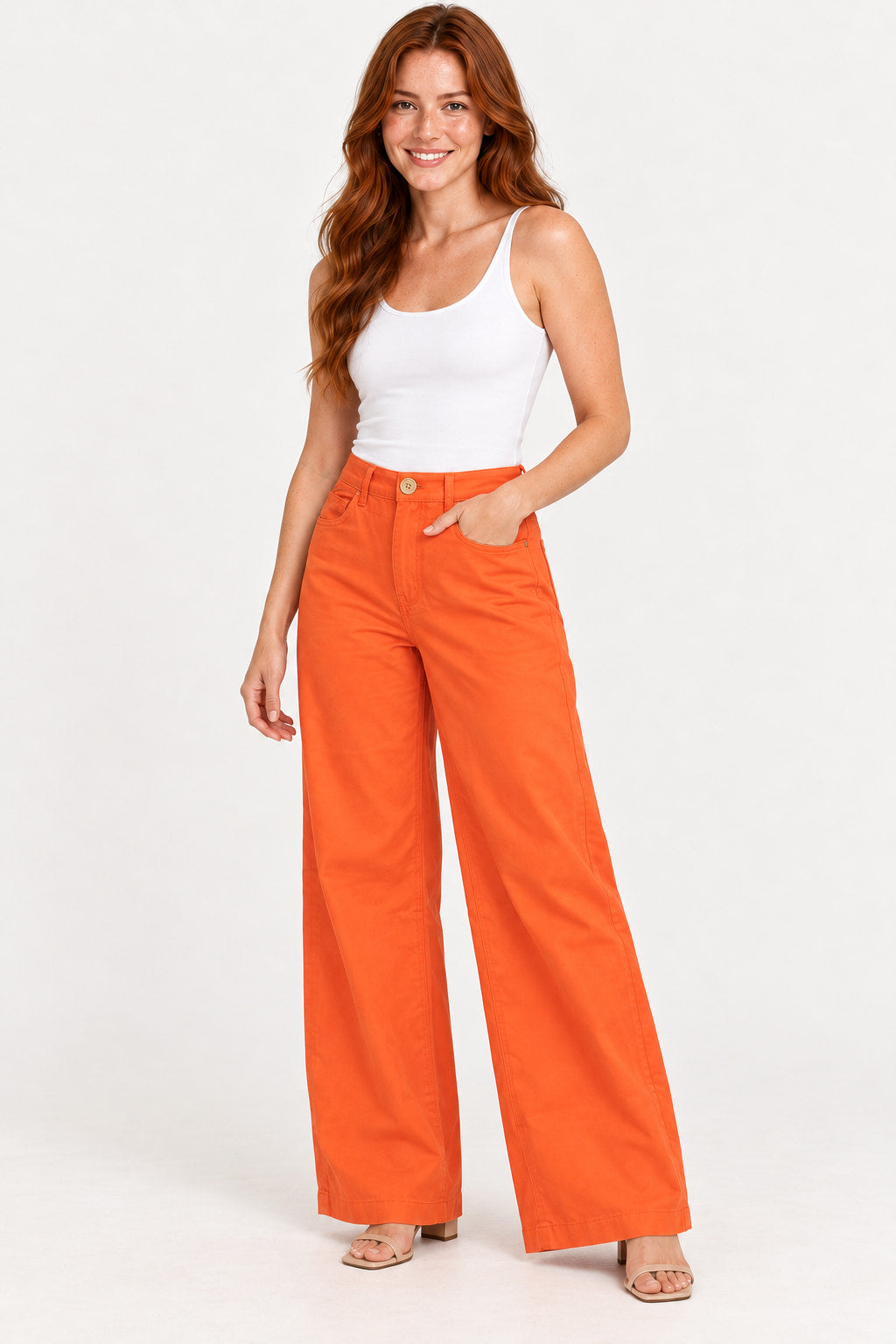 Laranja | Calça Alfaiataria Wide Revanche laranja de cintura alta, com a modelo de regata branca e uma mão no bolso