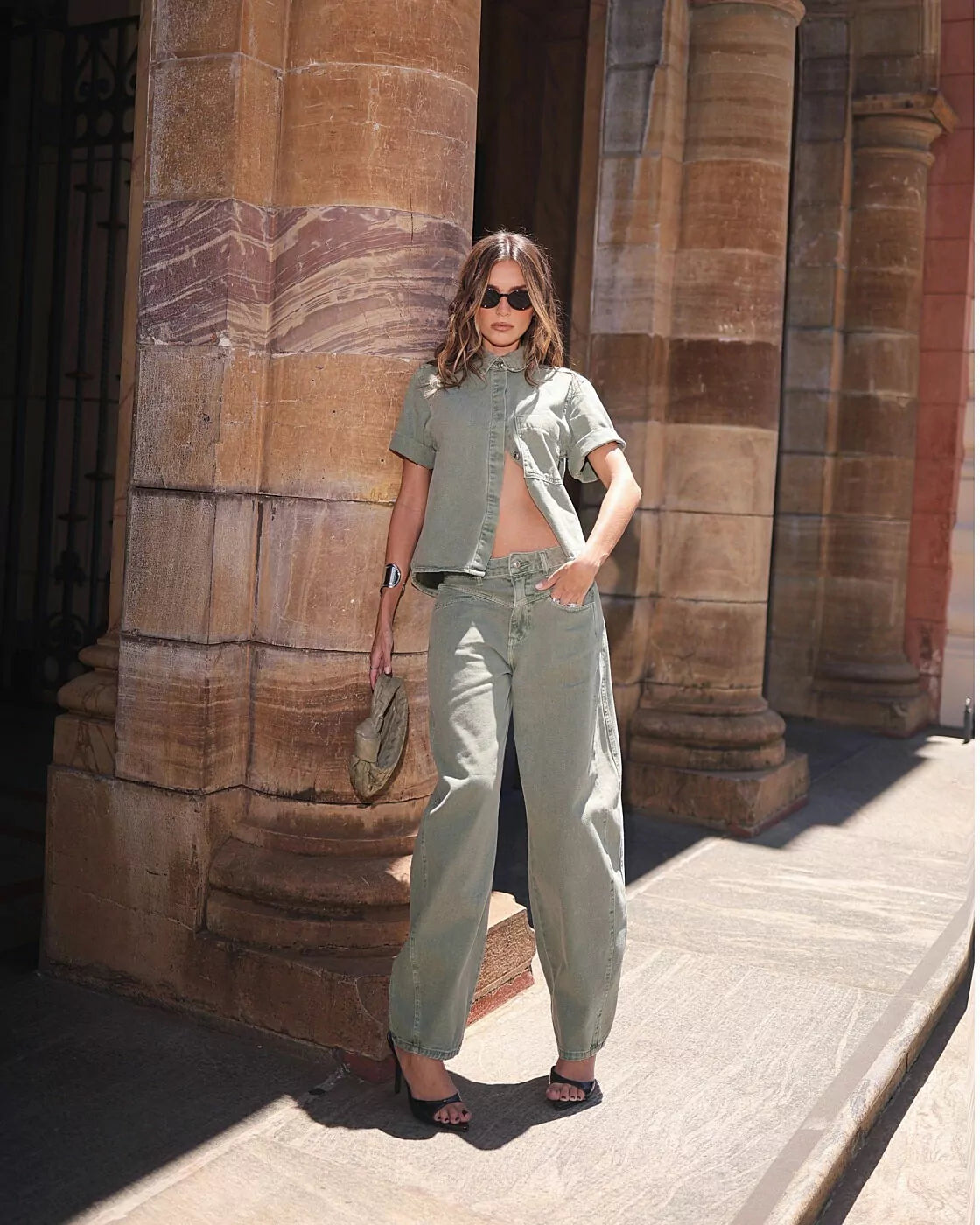 Calça Balloon Austin Alcance verde em look de camisa de manga curta verde, modelo de corpo inteiro em frente a colunas de ped