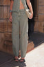 Calça Balloon Austin Alcance verde, vestida na modelo com cintura alta e pernas largas, detalhe do caimento em close