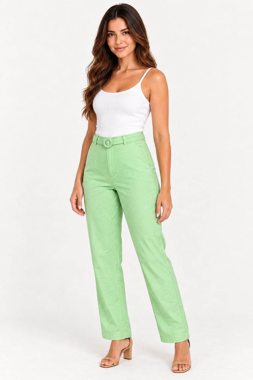 Verde | Calça Skenn verde claro de alfaiataria com cinto, modelo de regata branca e sandália bege, vista de frente em ângulo