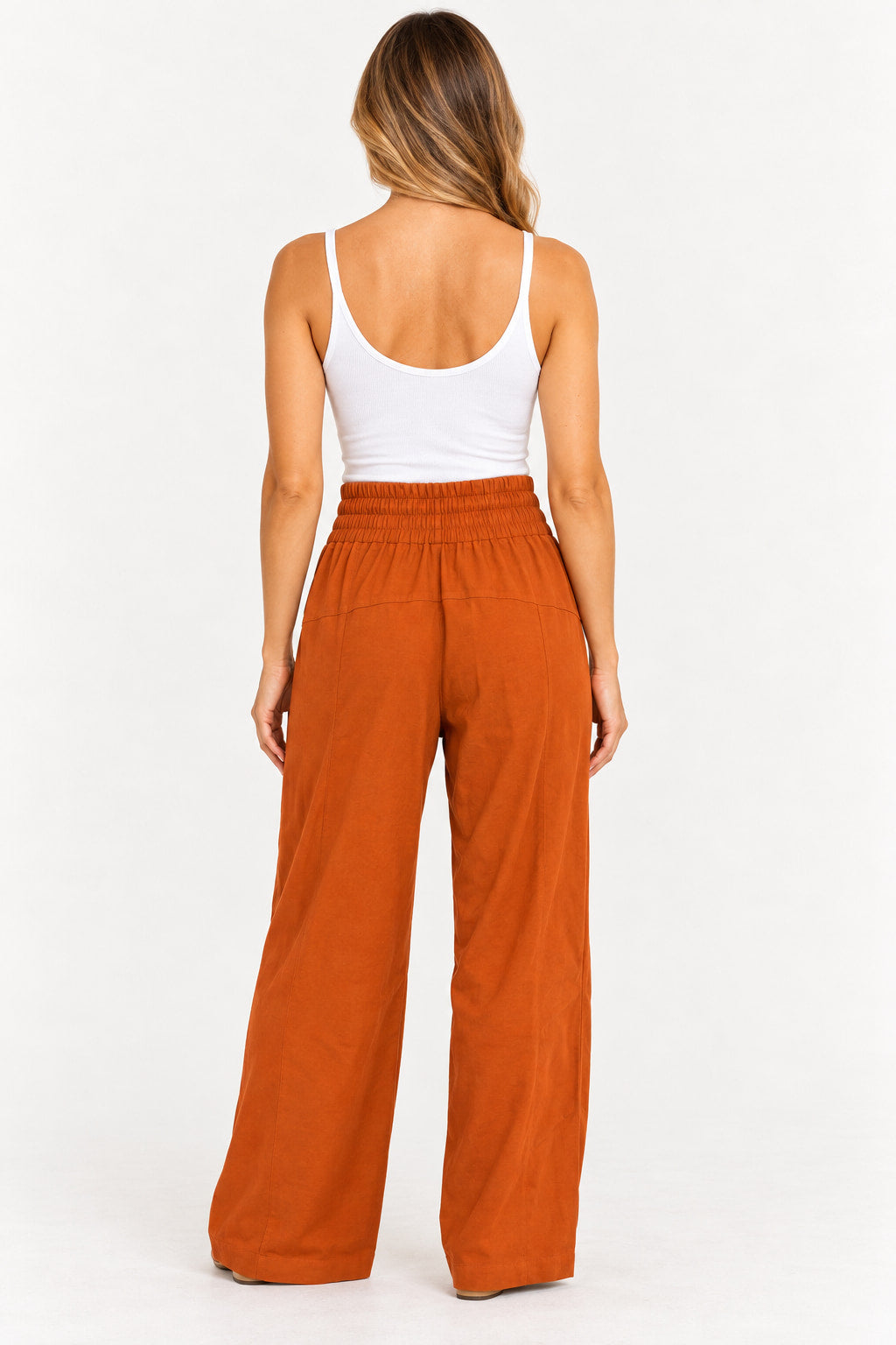 Caramelo | Calça pantalona Clamarroca caramelo vista de costas, com cintura elástica franzida e pernas largas