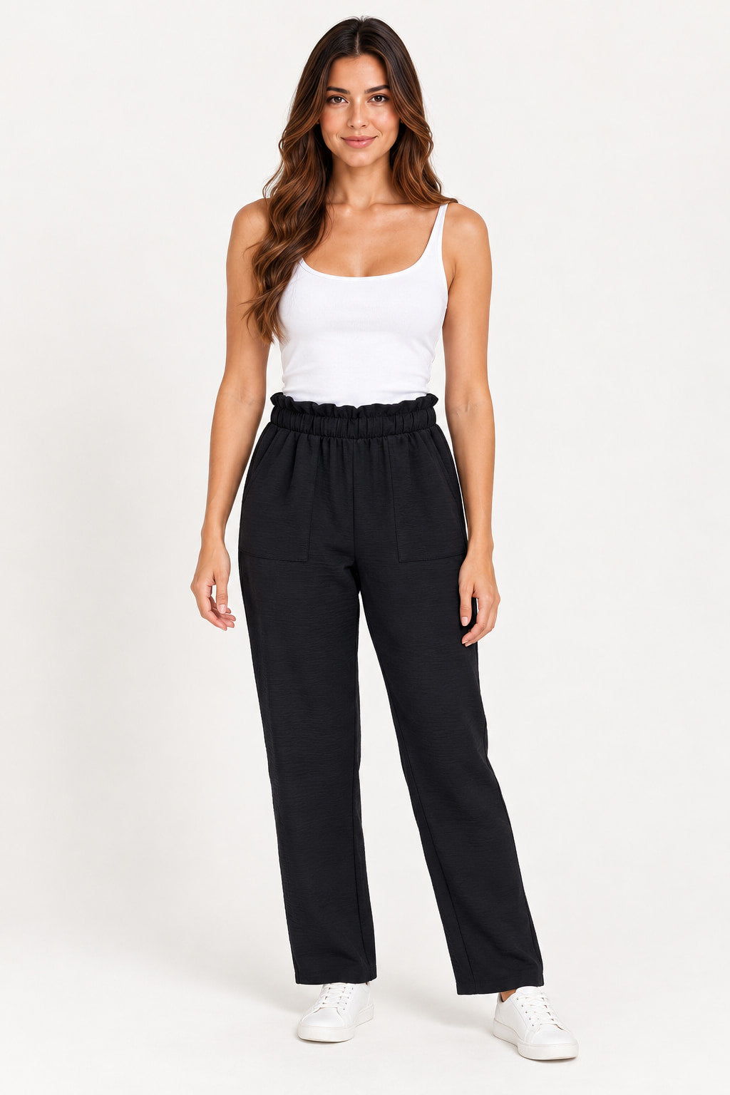 Preto | Calça Aishty Fresca Crepe preta de cintura alta com franzido, vestida na modelo com regata branca e tênis branco