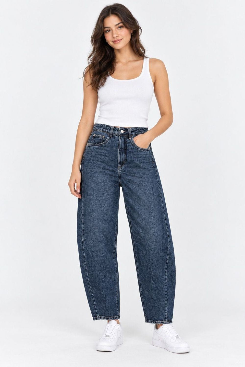 Jeans | Calça Jeans Baggy Cheer Escuro Lerrux em azul jeans, vestida na modelo com regata branca e tênis branco