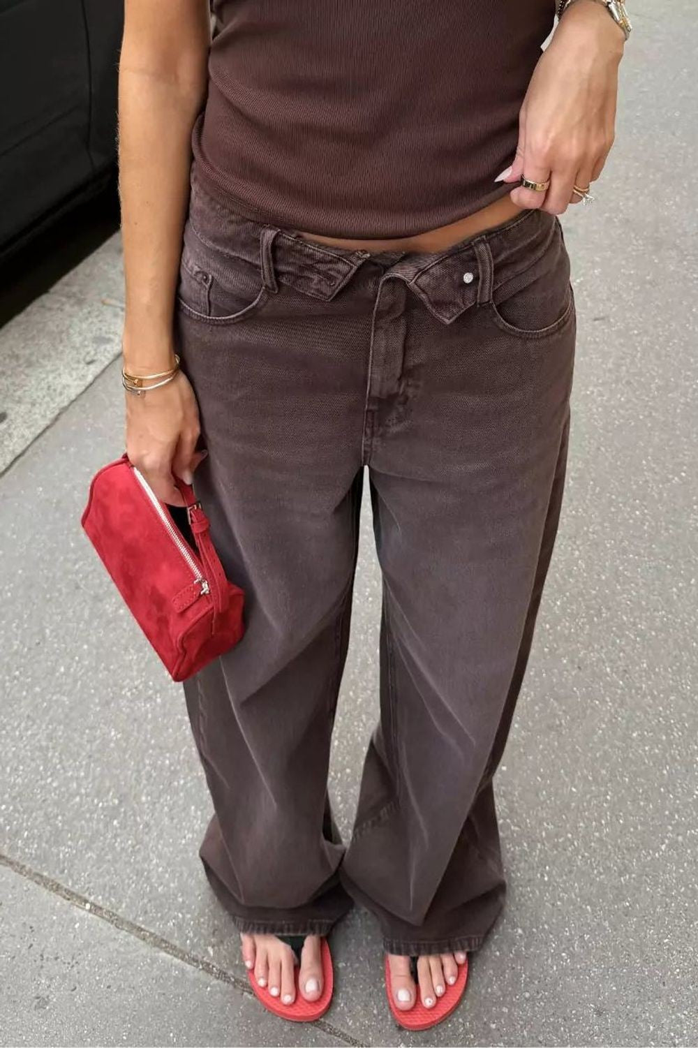 Calça jeans baggy Alcance marrom com cós overlap, vestida em modelo com blusa marrom e bolsa vermelha