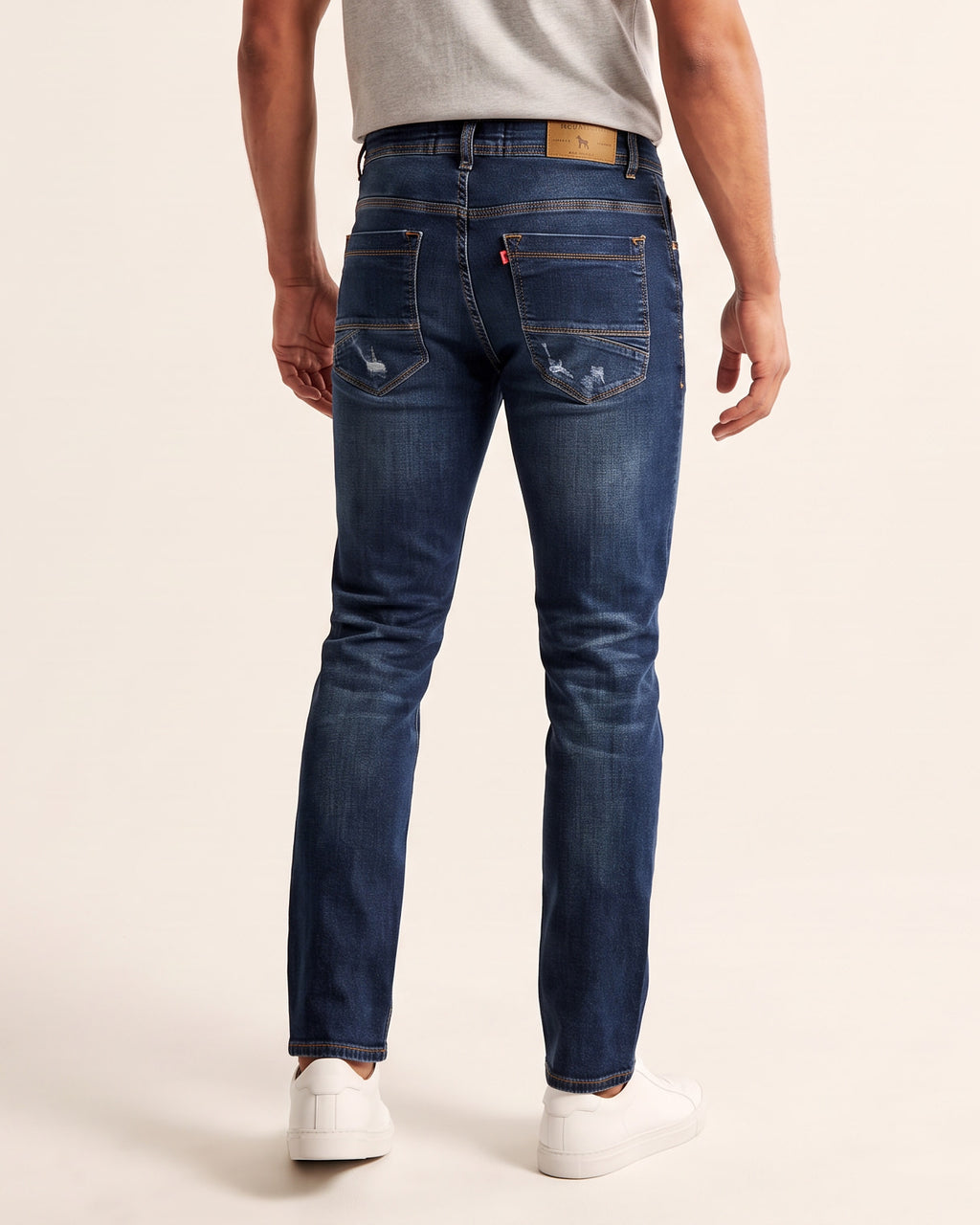 Calça Jeans Masculina Escura Revanche vista de costas, com bolsos traseiros e etiqueta de couro na cintura