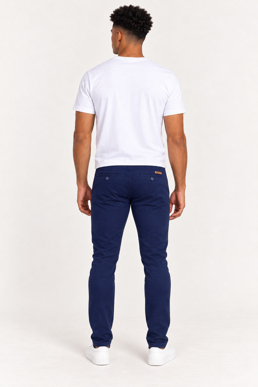 Azul Marinho | Calça masculina chino Revanche azul marinho vista de costas, com bolsos traseiros com botão e etiqueta da marca