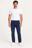 Jeans | Calça jeans masculina regular Revanche em azul escuro, vestida em modelo com camiseta branca e tênis branco, vista frontal