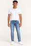 Jeans | Calça Revanche jeans masculina de barra normal, azul jeans, vestida em modelo de camiseta branca e tênis branco, vista de fre