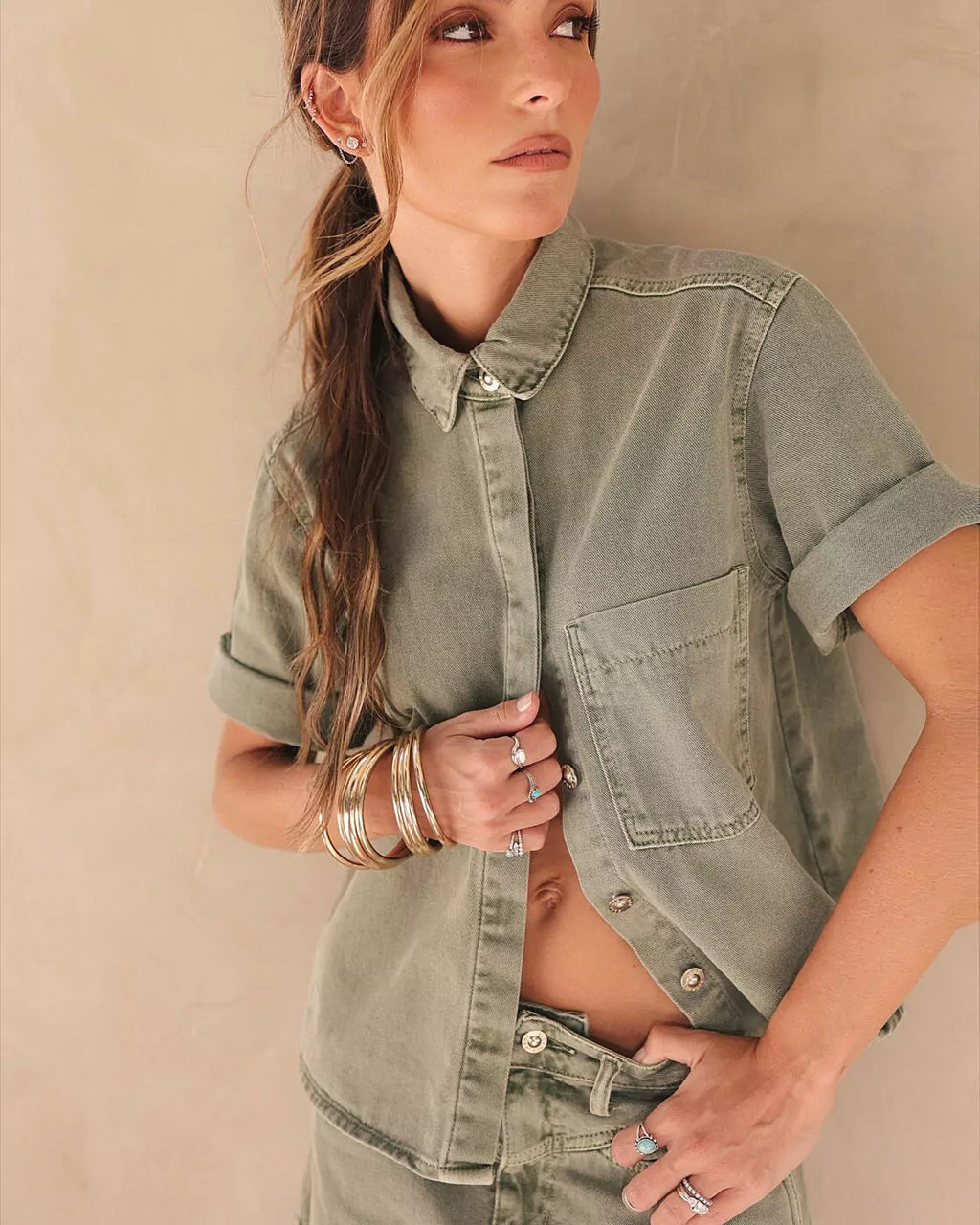 Camisa Essential Alcance verde de manga curta com botões dourados, detalhe do bolso no peito e da gola na modelo