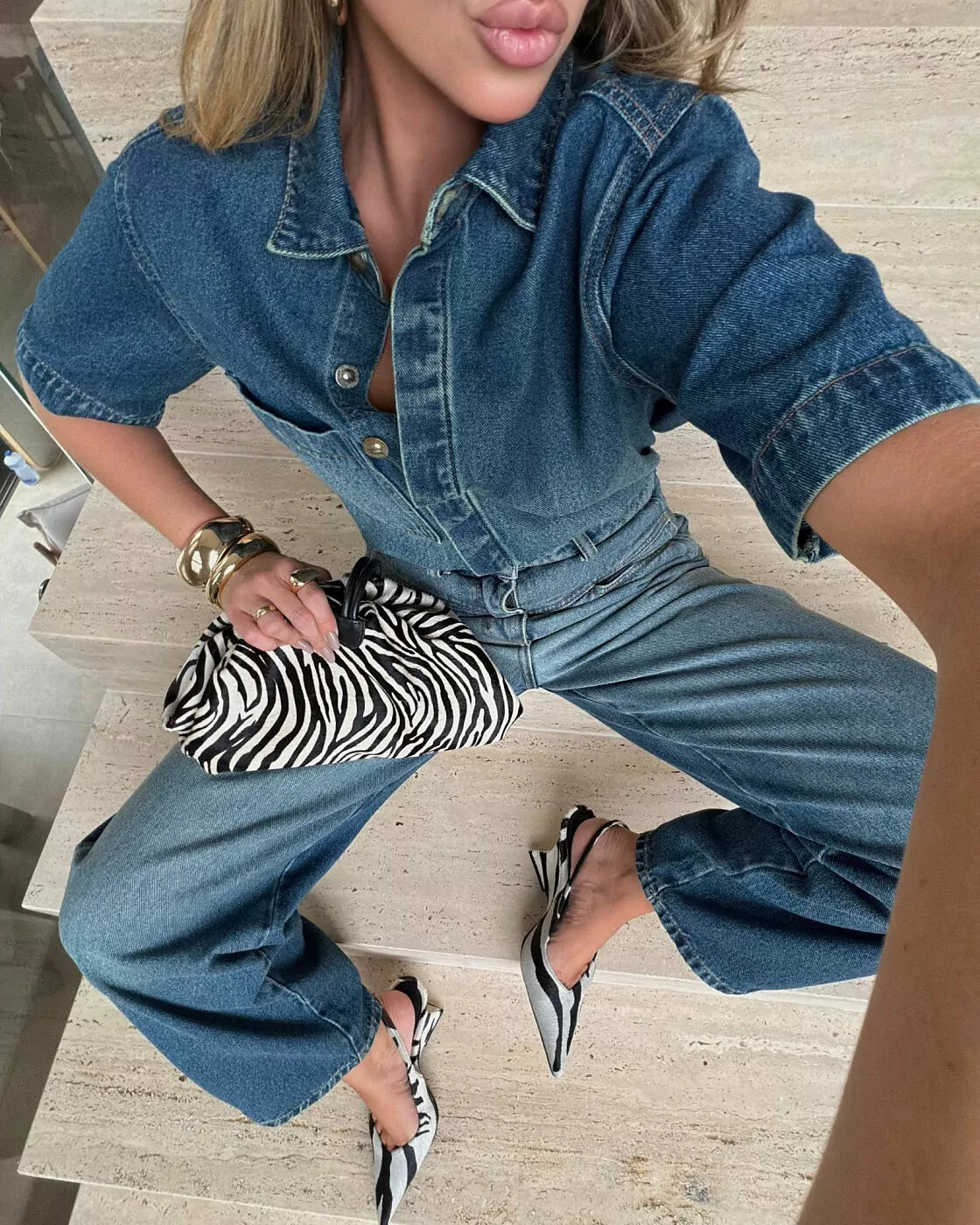 Camisa Jeans Essential Alcance em jeans de botões dourados combinada com calça jeans e sling de zebra