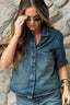 Camisa Jeans Essential Alcance em jeans, vestida na modelo com óculos escuros, com bolso no peito