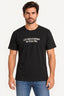 Preto | Camiseta Revanche masculina manga curta preta com estampa de letras brancas no peito, vestida em modelo de frente