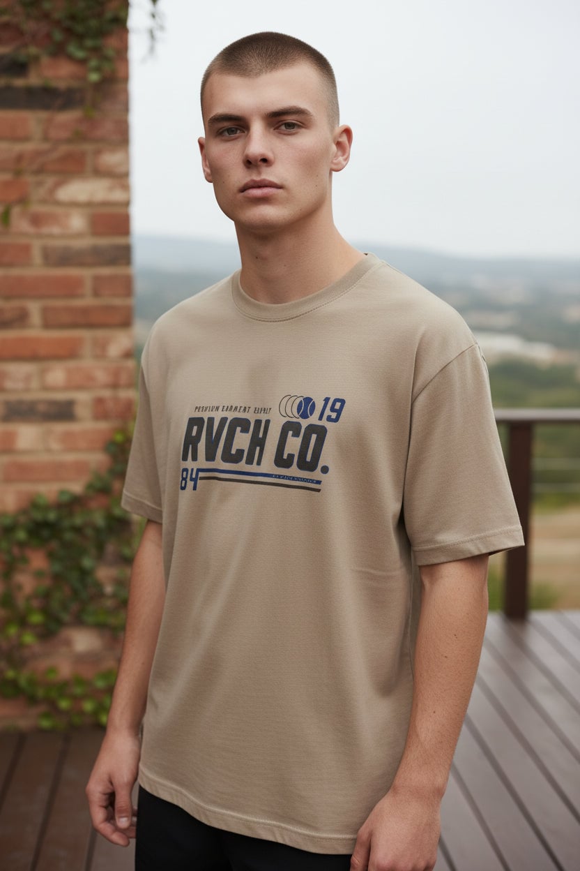 Camiseta Masculina Estampa Gola Careca Revanche bege areia com estampa RVCH CO. em close na frente, vestida em modelo Imagem principal do produto