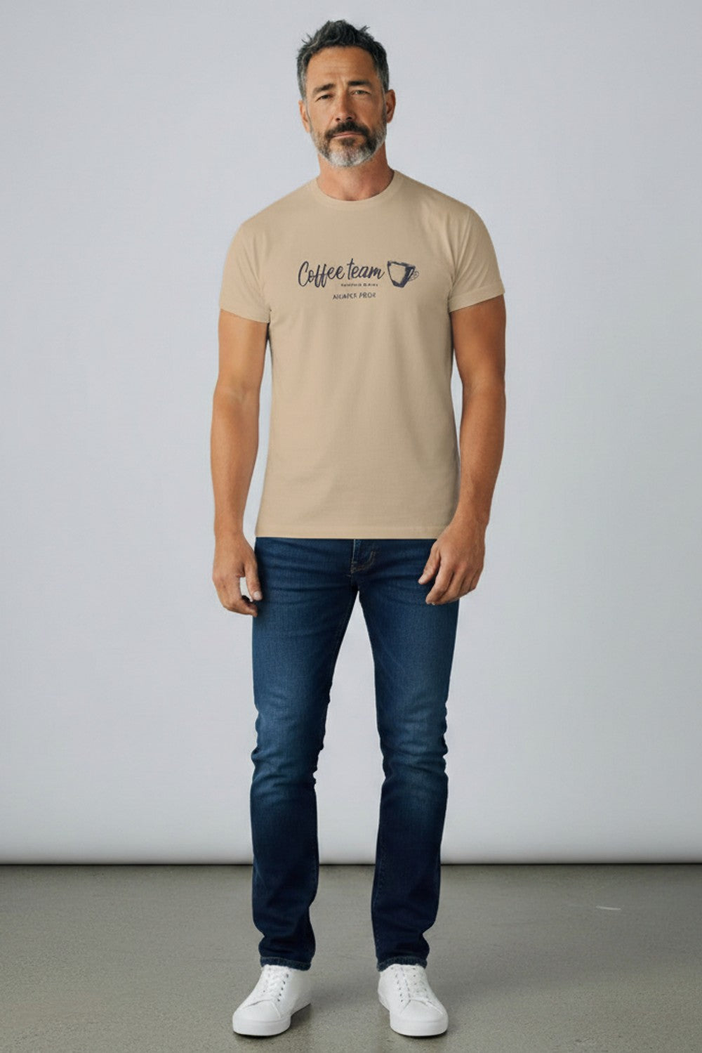 Camiseta masculina estampada Revanche em cor areia, com estampa Coffee team na frente, vestida em modelo com calça jeans escu Imagem principal do produto