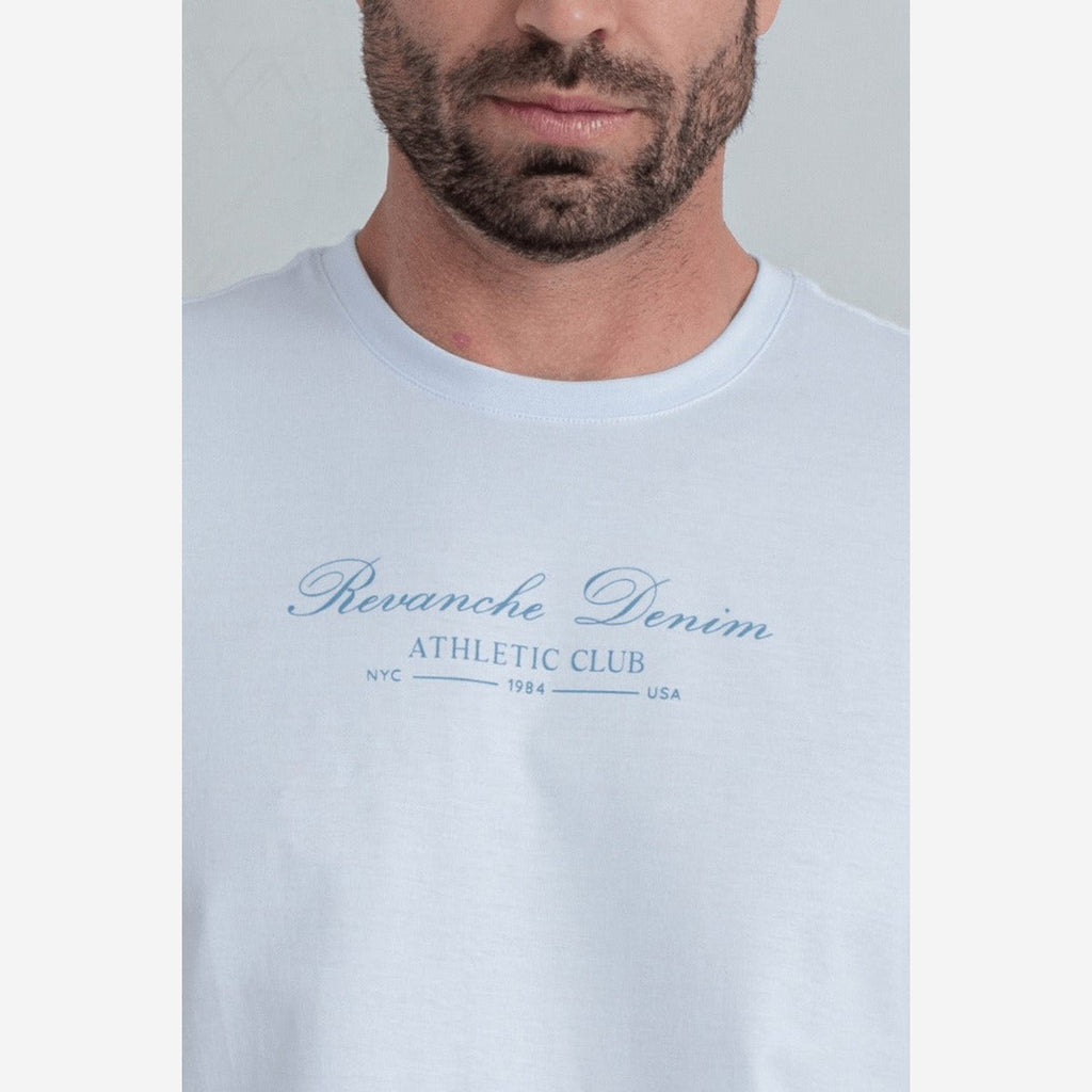 Camiseta Masculina Manga Curta Estampada Revanche branca, detalhe da estampa azul Revanche Denim Athletic Club no peito