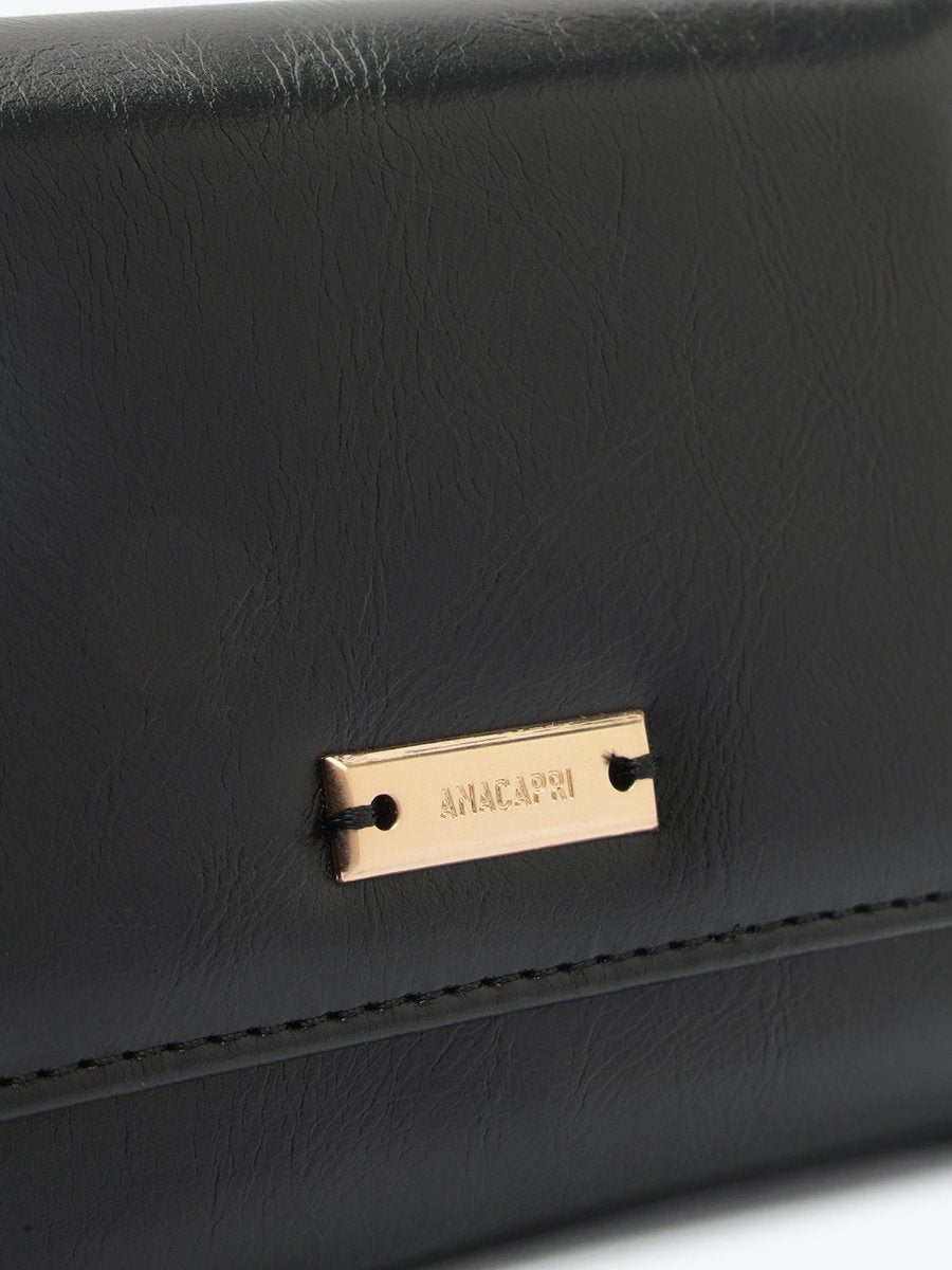 Detalhe da carteira Anacapri Rustic preta com placa dourada da marca no fecho