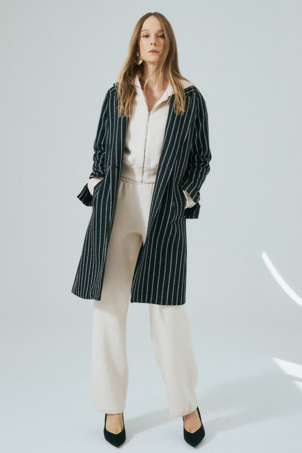 Casaco Tweed Listrado Skenn preto com listras brancas, vestido em modelo com calça bege e sapato preto Imagem principal do produto