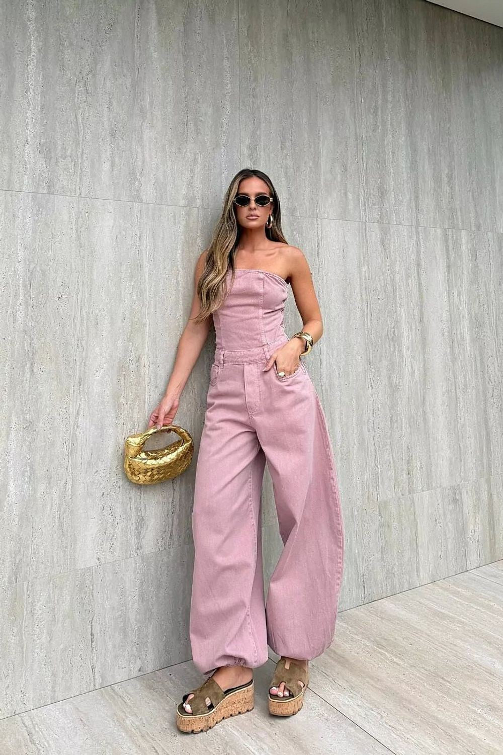 Macacão Aladim Cloud Alcance rosé, tomara que caia, com calça de perna larga e barra franzida, usado por modelo em frente a p
