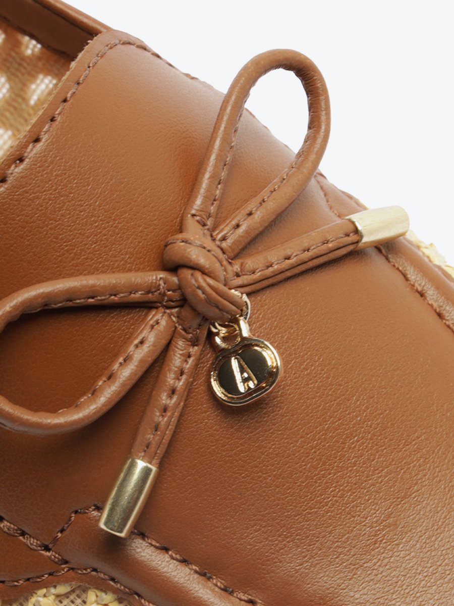 Detalhe do laço do mocassim Anacapri marrom com pingente dourado com letra A