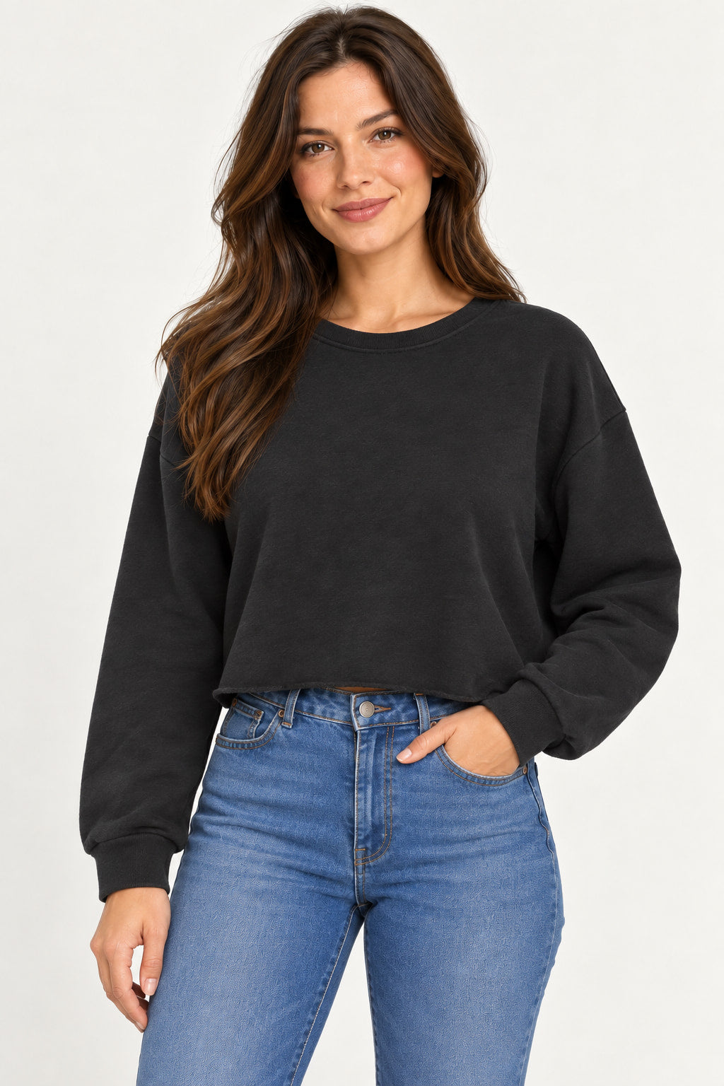 Preto | Moletom Cropped Alcance preto de manga longa e barra cortada, com a modelo com a mão no bolso da calça jeans