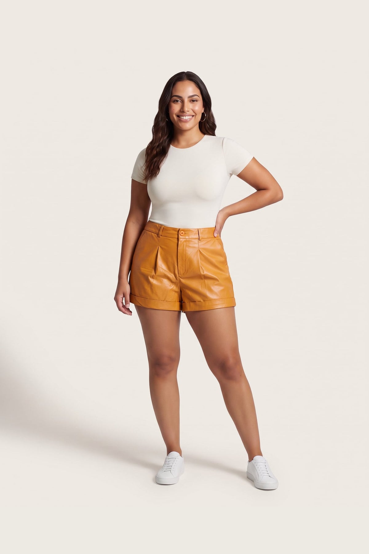 Shorts Skenn couro alfaiataria mostarda, modelo de corpo inteiro com blusa off-white e tênis branco Imagem principal do produto